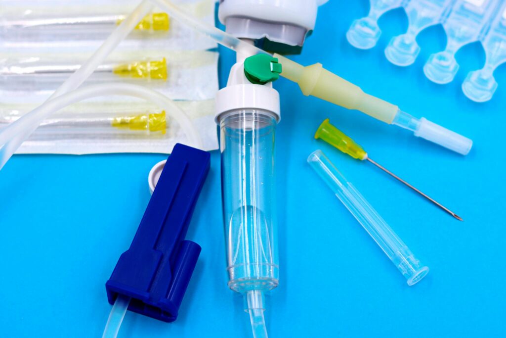 Collection of sterile medical tools including syringes and tubing against a blue backdrop.